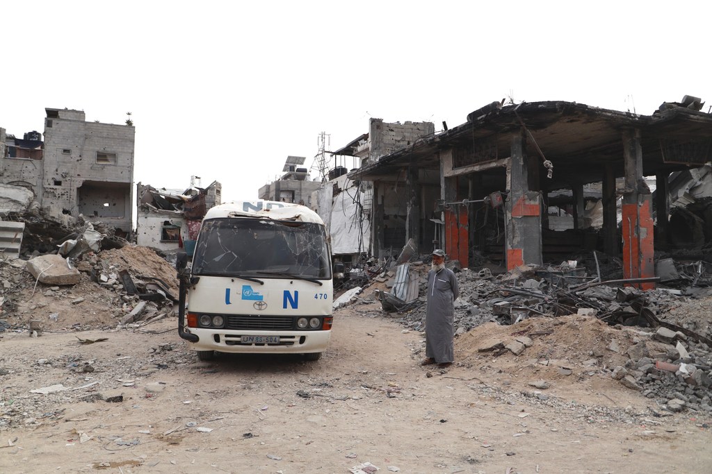Un Palestinien se tient à côté d'un véhicule des Nations Unies détruit.